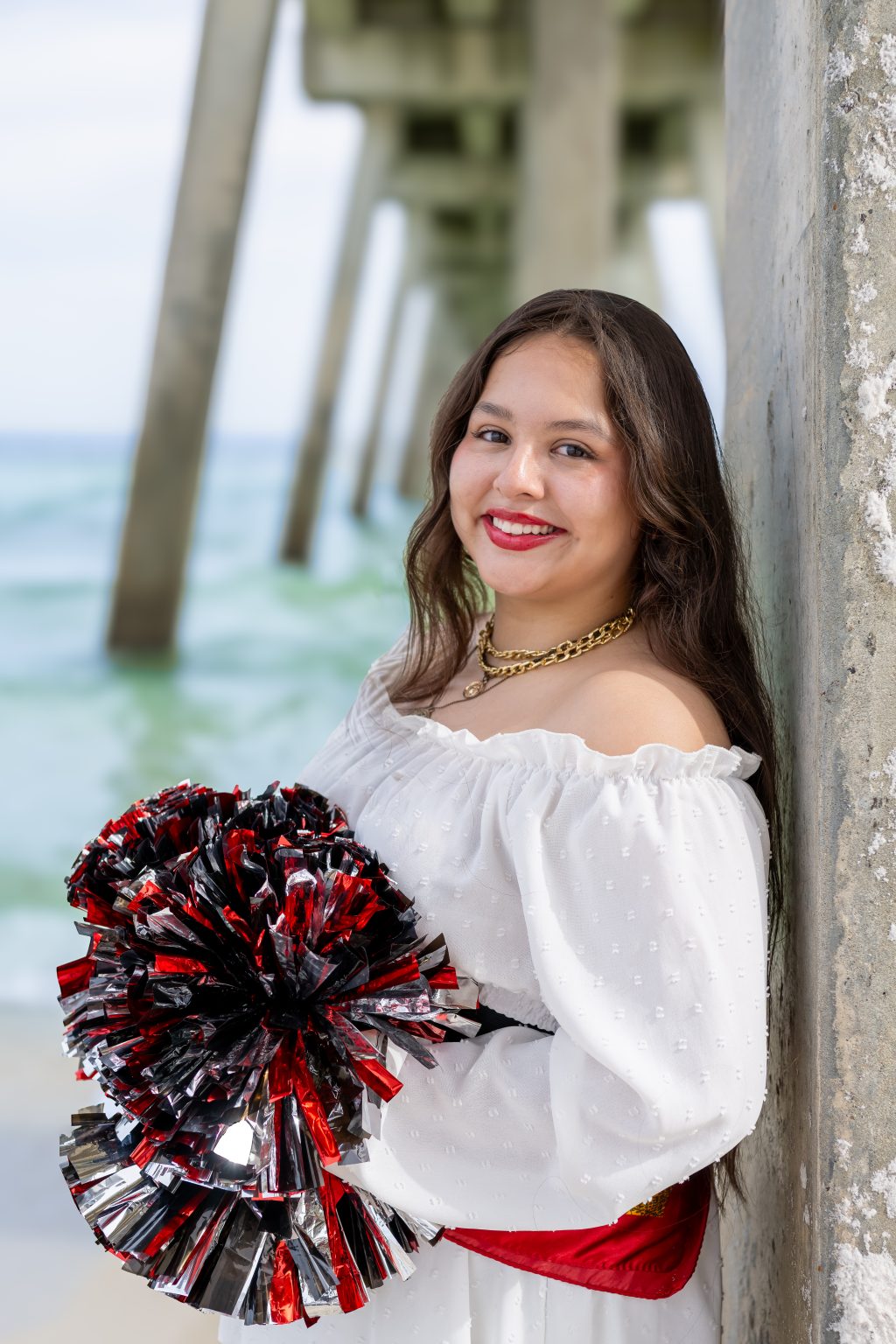 Senior cheerleader with pom poms beneath the pier