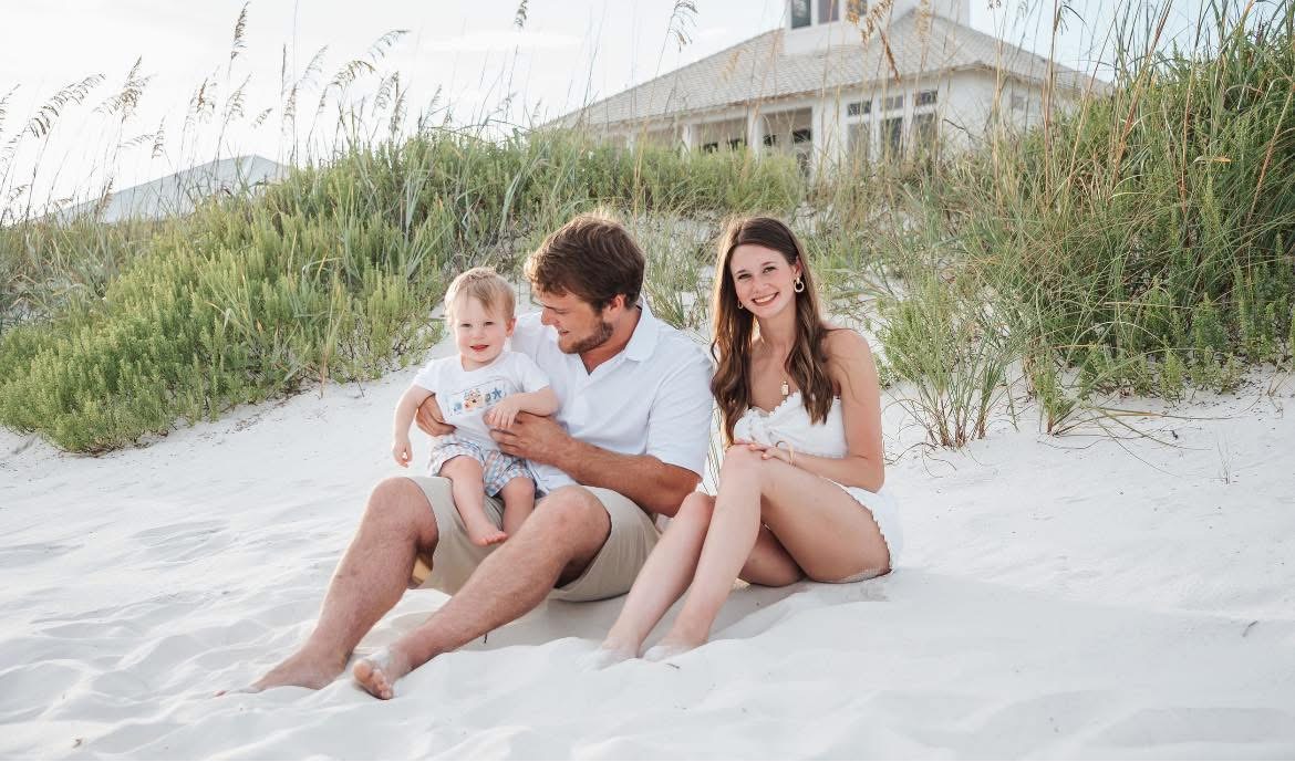 Young family cuddled together among the sea oats during a Navarre Beach family session