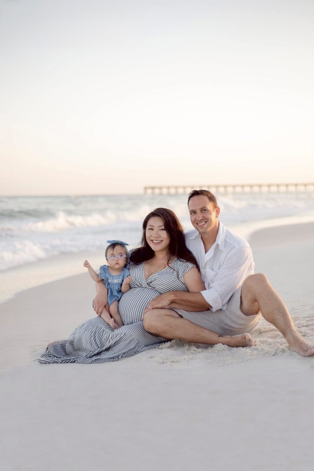Family seated together at the shoreline during a sunset mini session