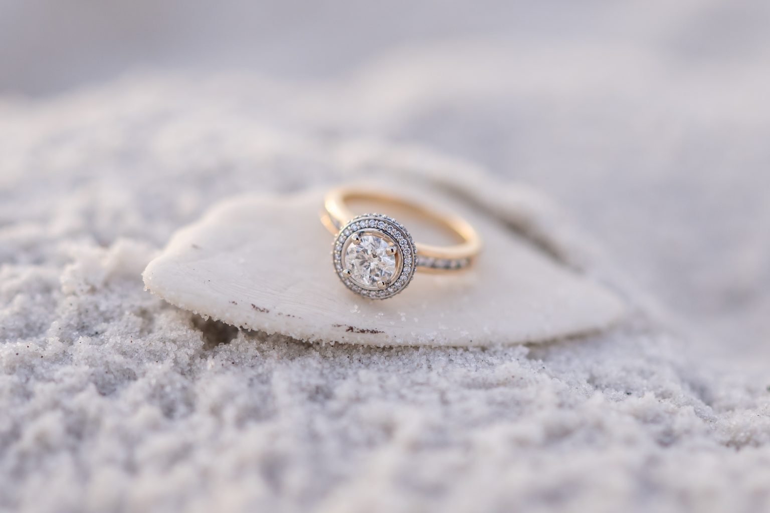 Engagement ring resting in the white sand