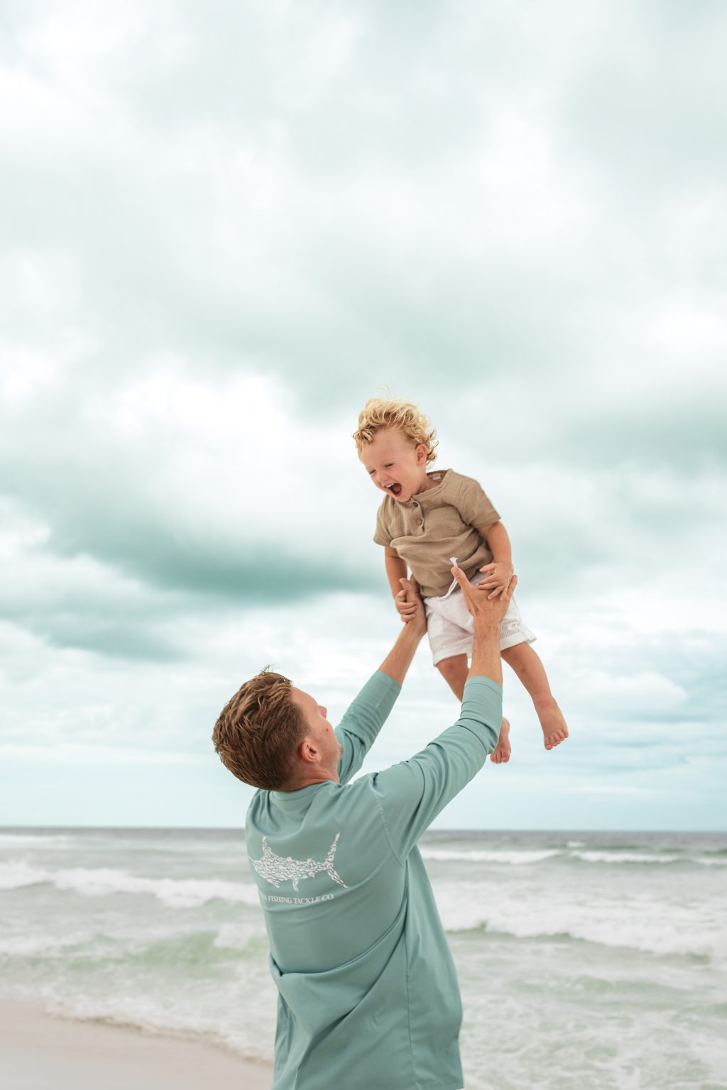 Dad tossing his little one into the air at the beach