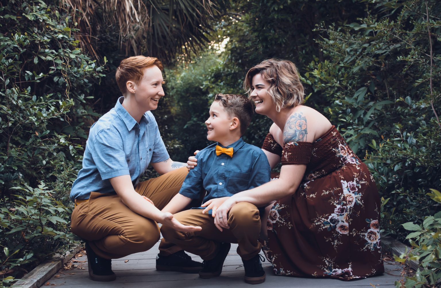 Family of three laughing together on a garden path