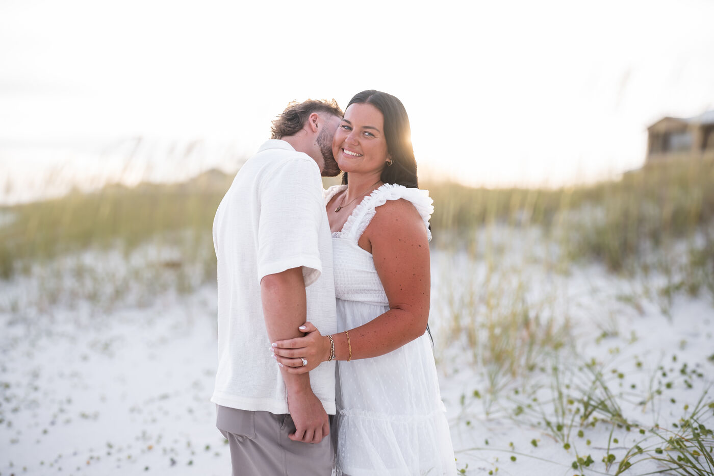 Couple sharing a kiss among the sea oats on a white sand dune