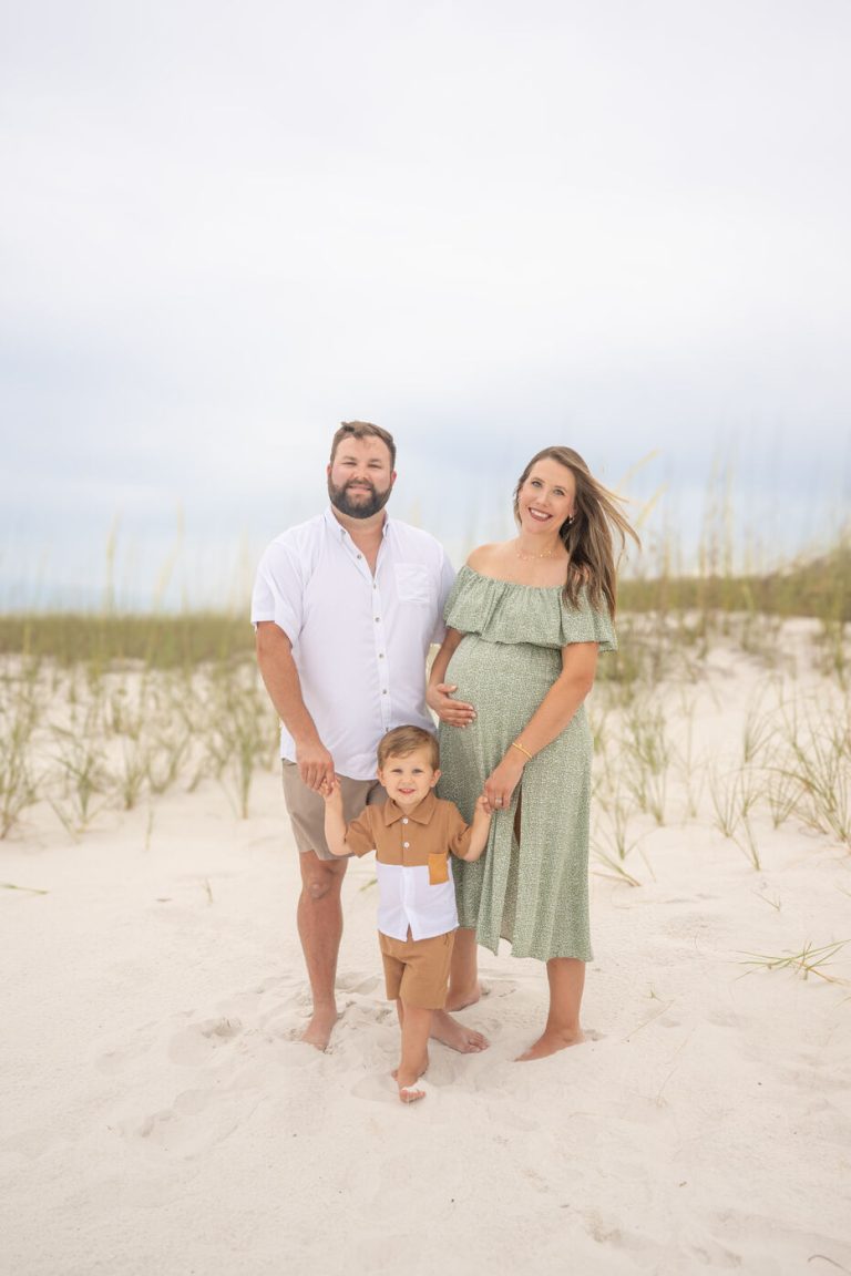 Expecting parents walking the shoreline at sunset