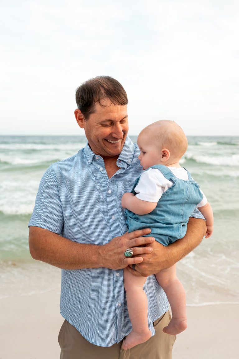Dad holding his little boy at the water’s edge in Navarre Beach